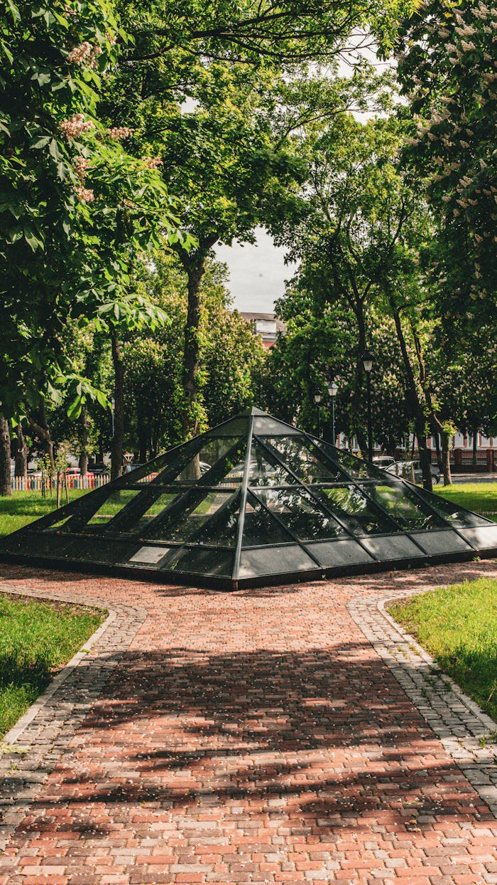 A modern glass pyramid surrounded by vibrant trees in Kamianets-Podilskyi, Ukraine.